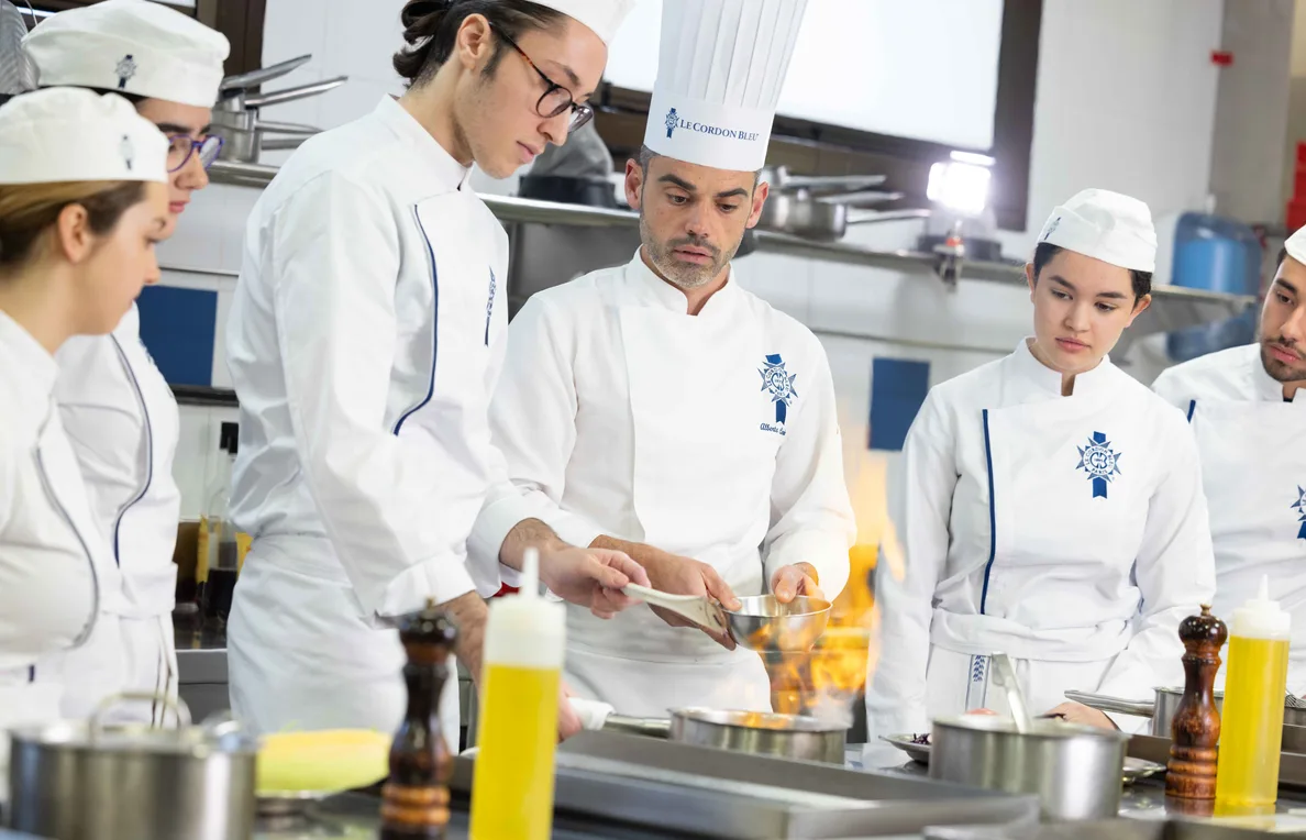 Un chef instruye a un grupo de estudiantes de Gastronomía en la cocina del campus